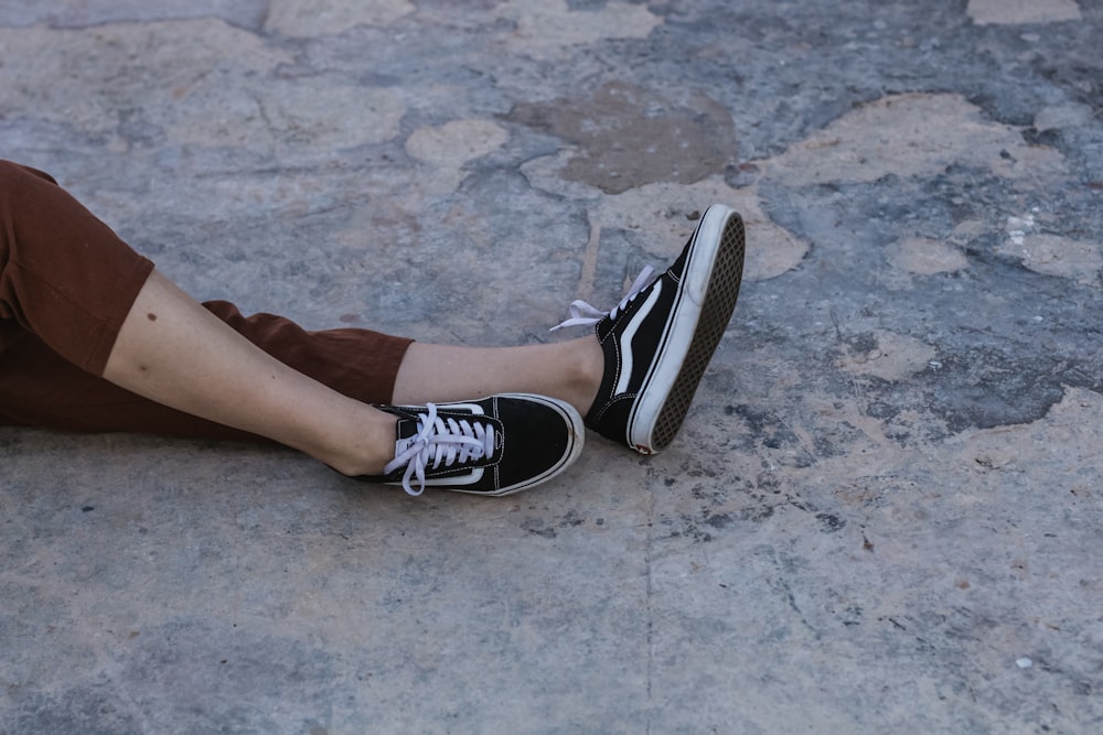 검은색 Vans Old Skool 신발 한 켤레를 신고 바닥에 누워 있는 사람