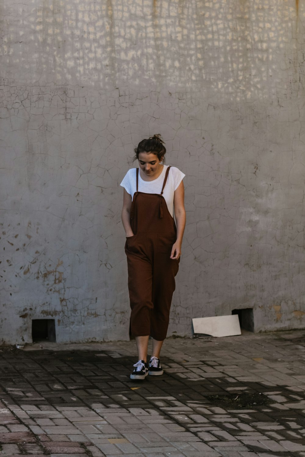 standing woman beside gray concrete wall