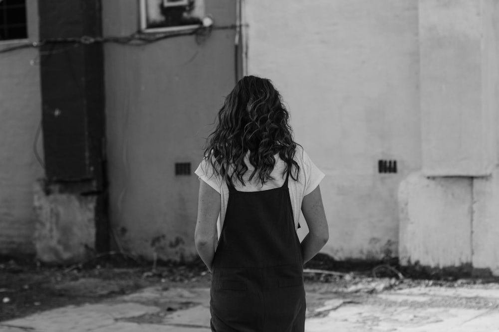 grayscale photography of woman standing near house