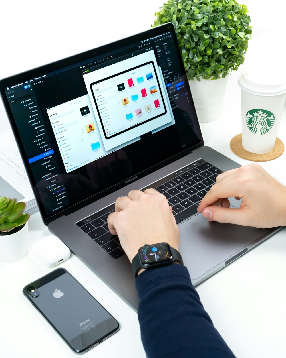 person using laptop between Starbucks cup and iPhone