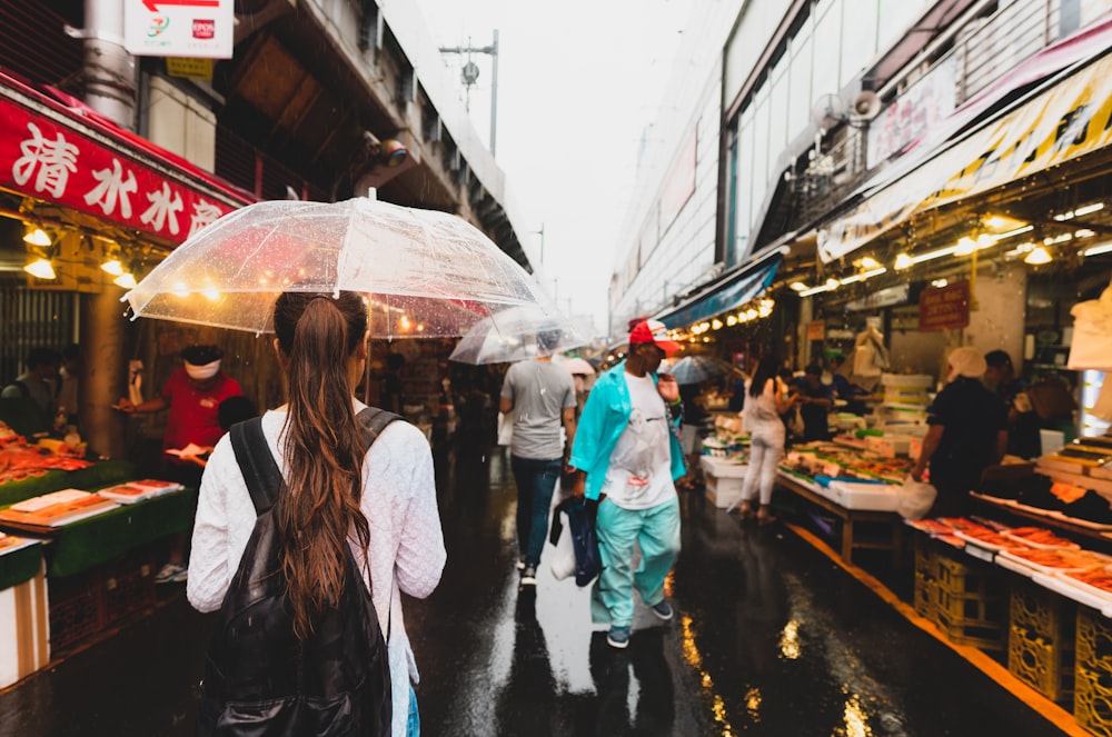 people walking with umbrella on alley between store stalls