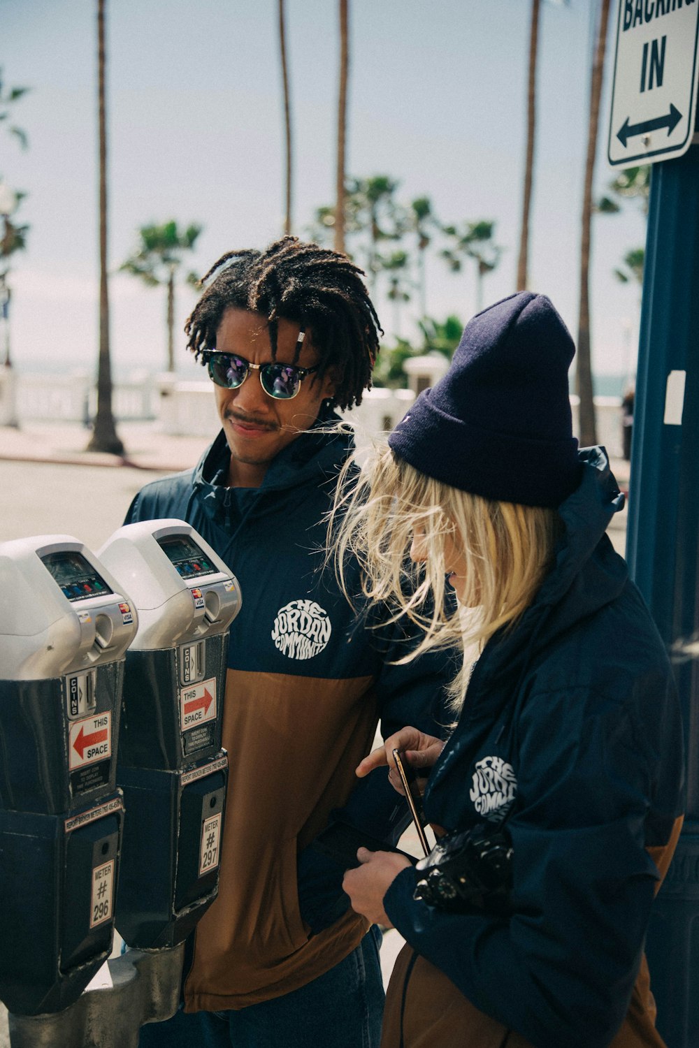 man and woman standing beside parking meters