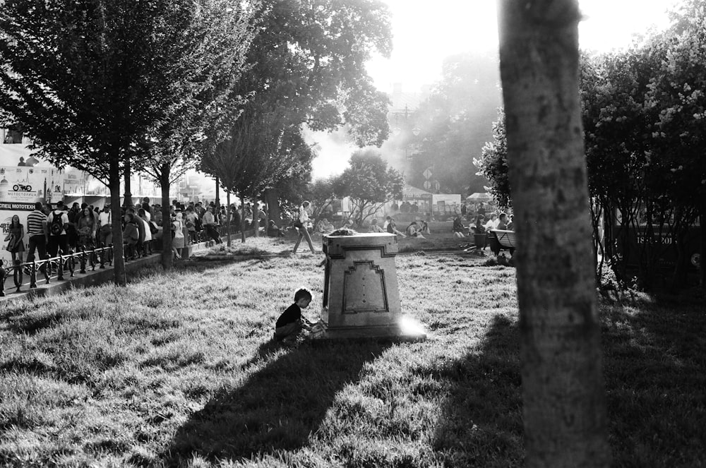 child sitting near the pillar on the grass