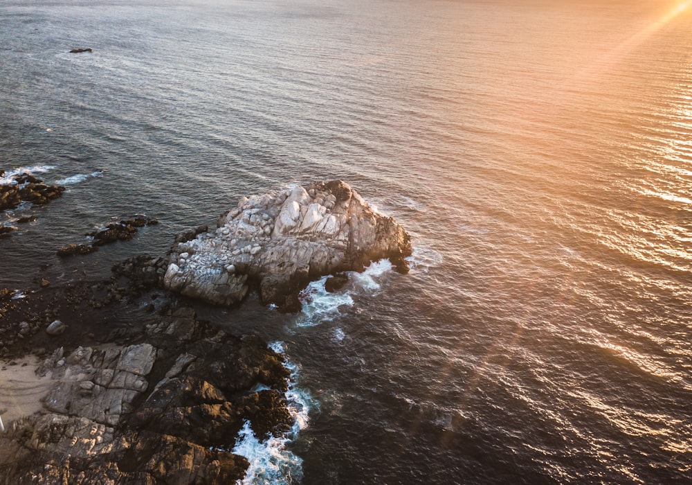 an aerial view of the ocean with a rock outcropping