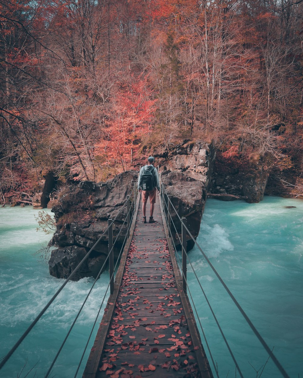 man on brown bridge near trees