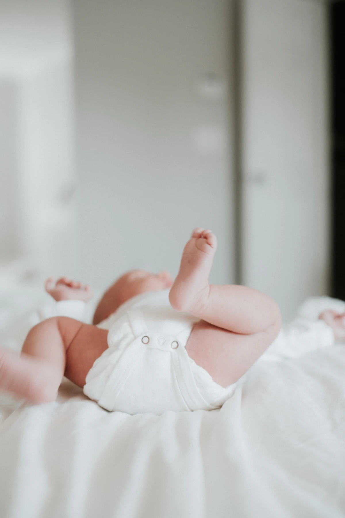 Em bé mặc bỉm nằm ngửa trên giường