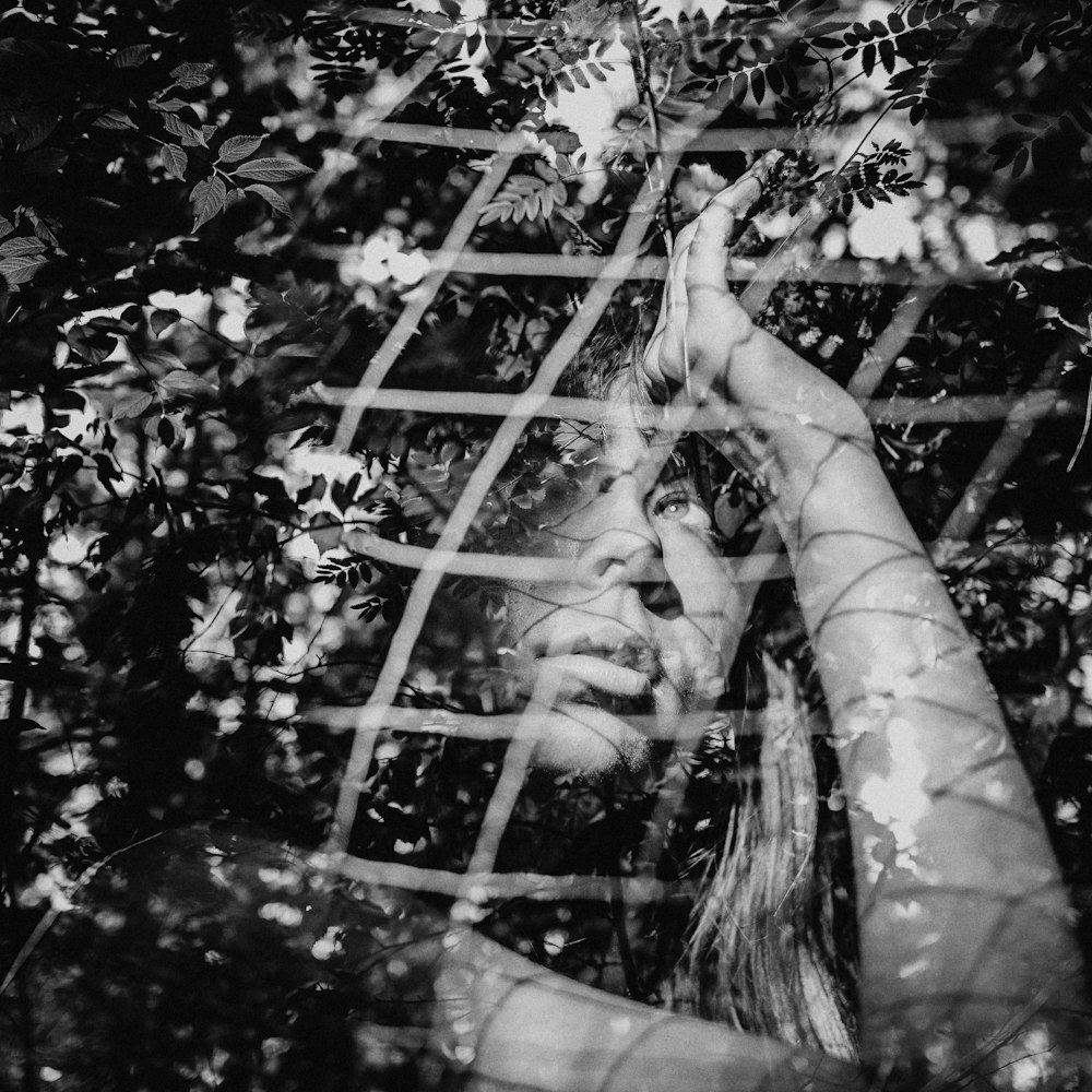 greyscale photo of woman under fence