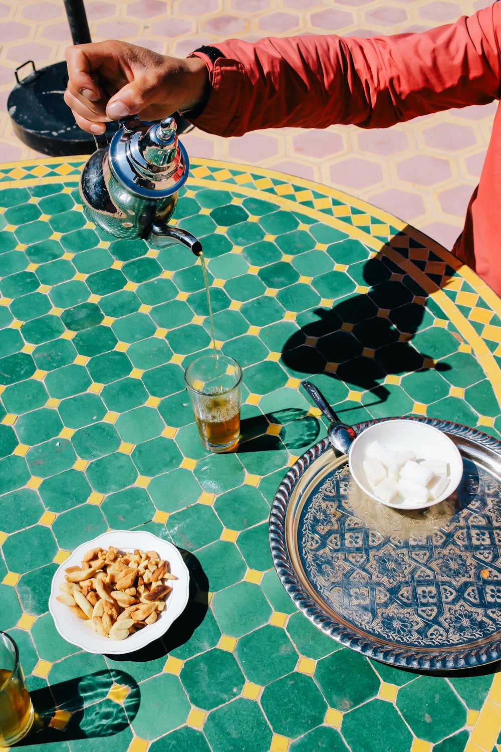 person pours tea to clear glass cup on table