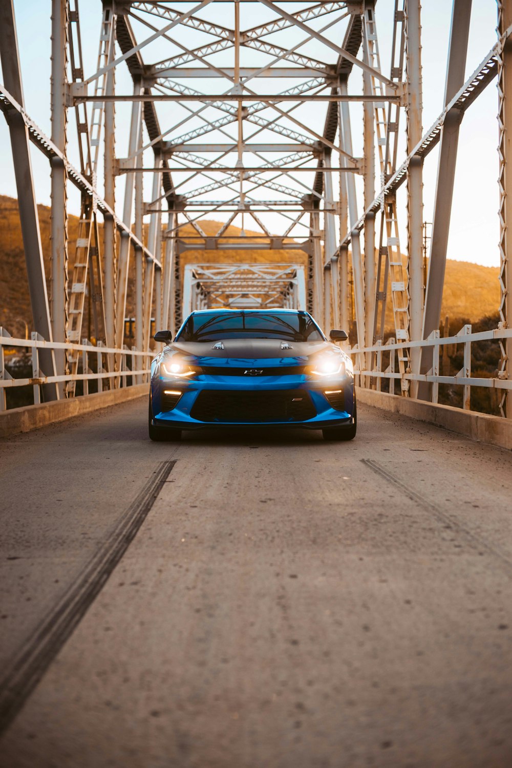 blue Chevrolet Camaro running on bridge during daytime