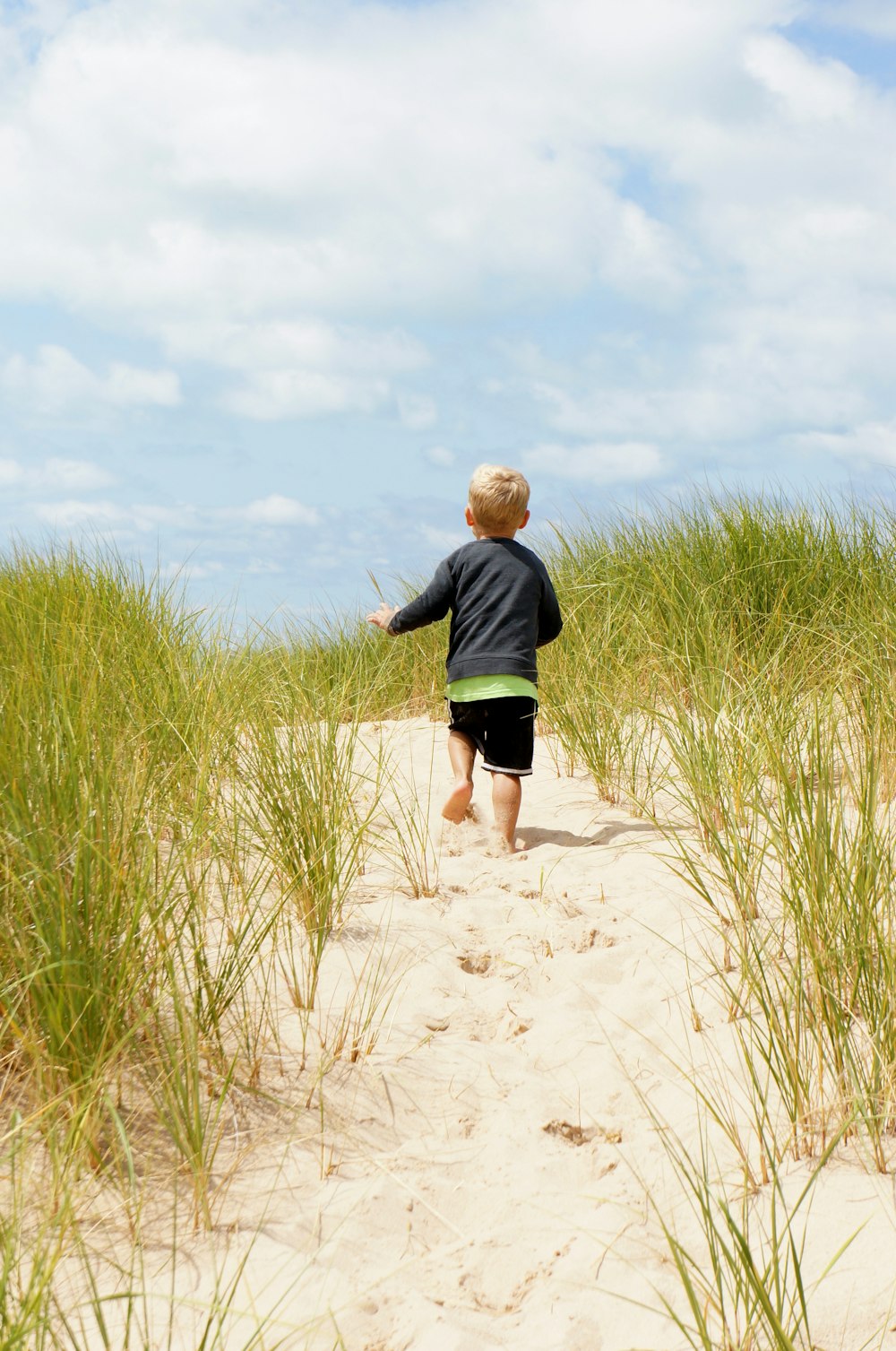 Junge läuft tagsüber auf Sand