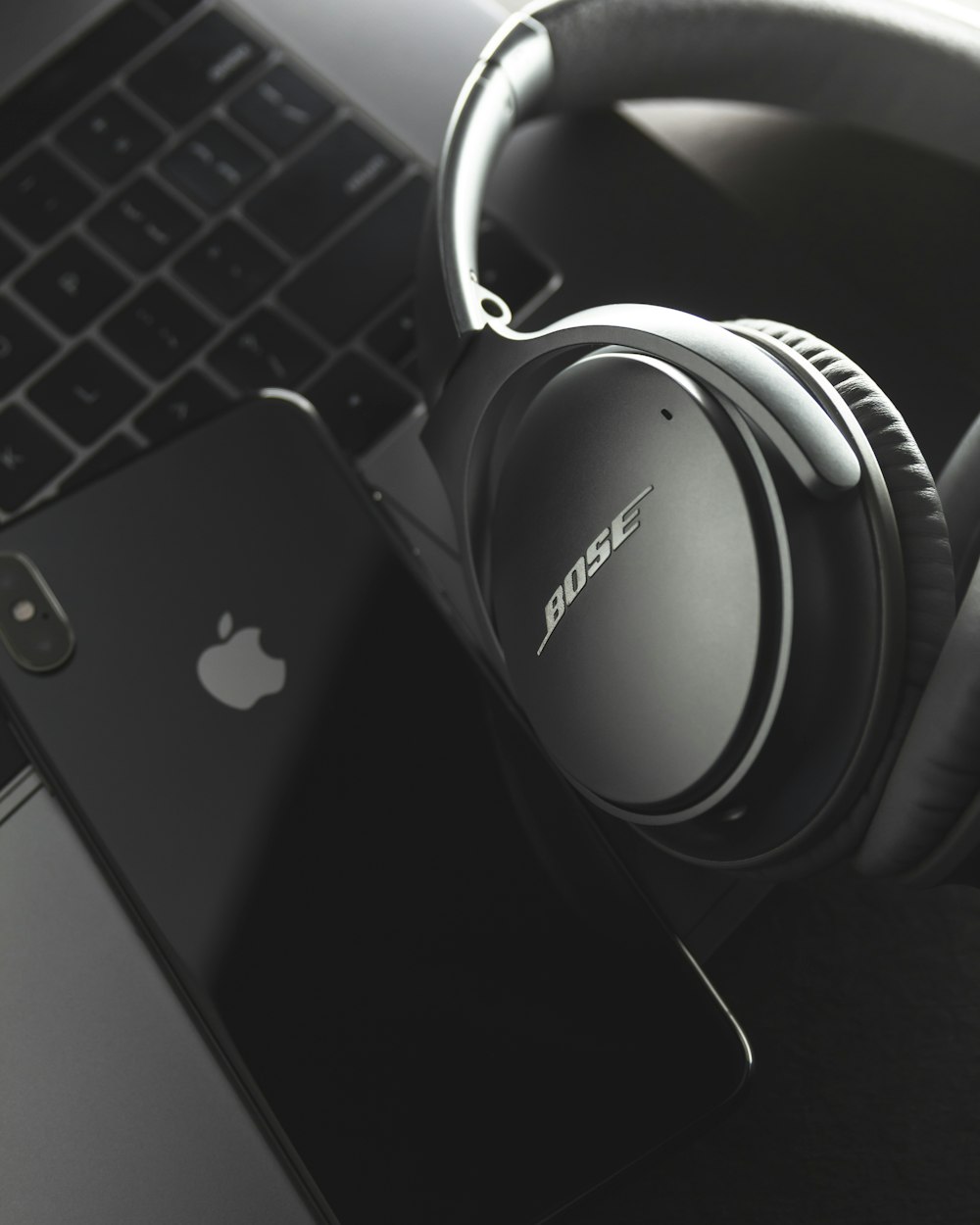 gray and black Bose headset and black iPhone X