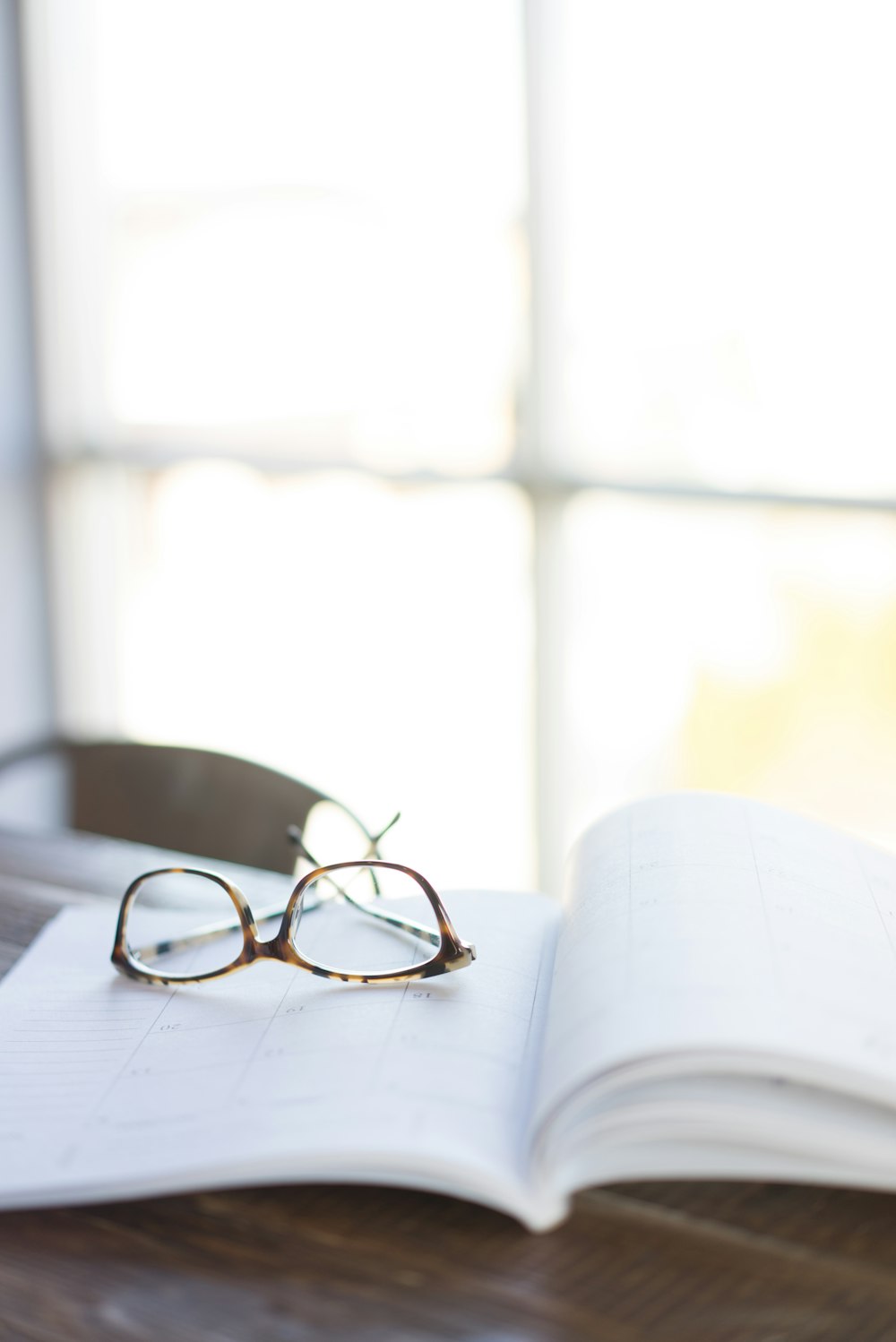 brown framed eyeglasses on top of open book