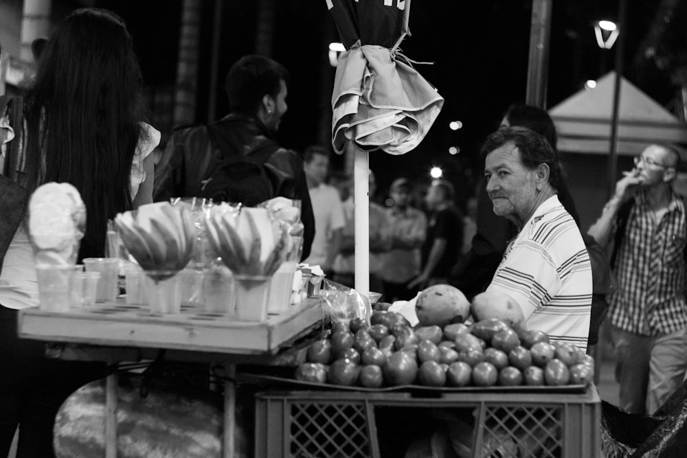 man sitting beside fruit stand
