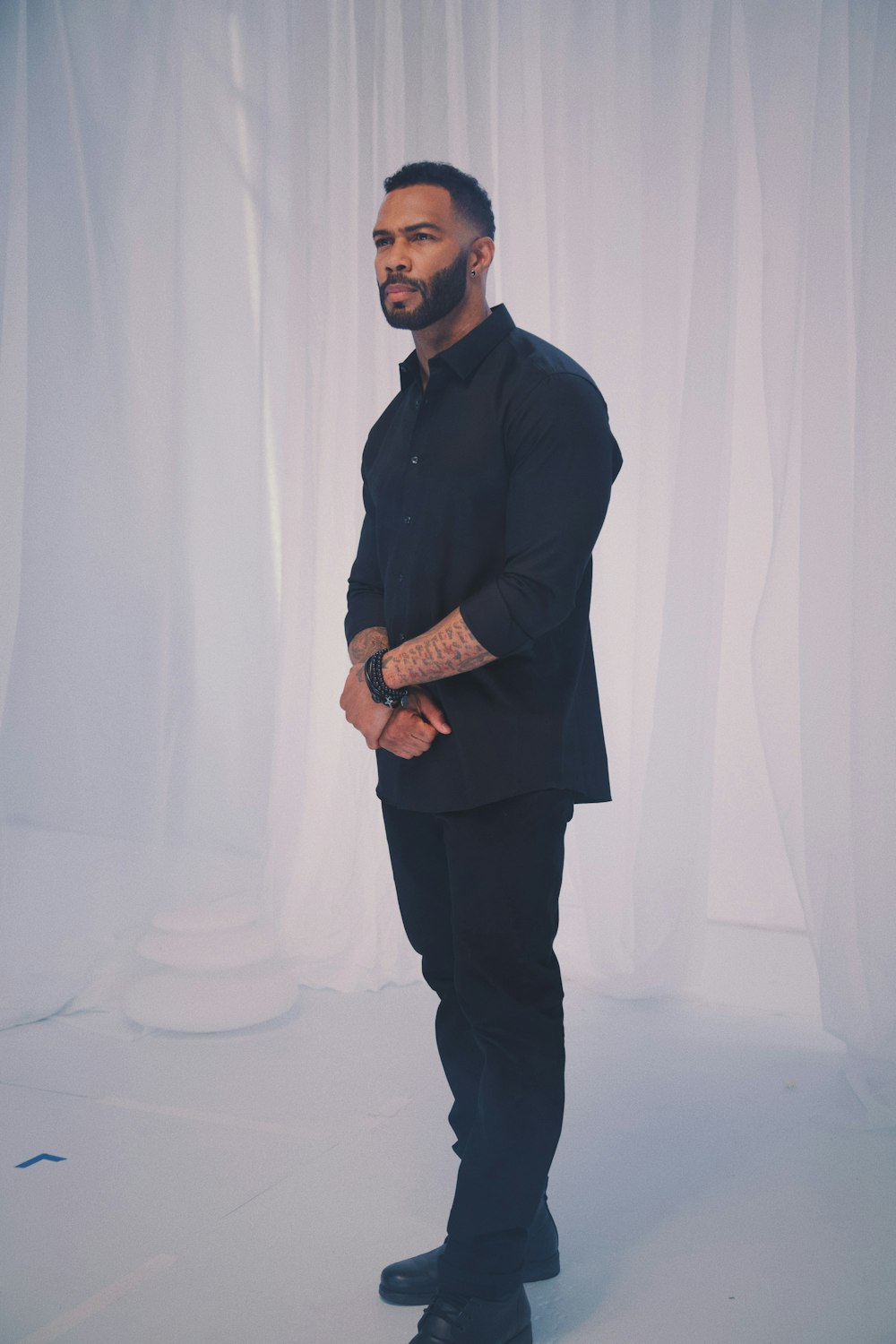 man wearing black jacket standing near white curtain