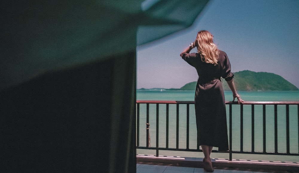 woman in brown robe stands in porch overlooking sea