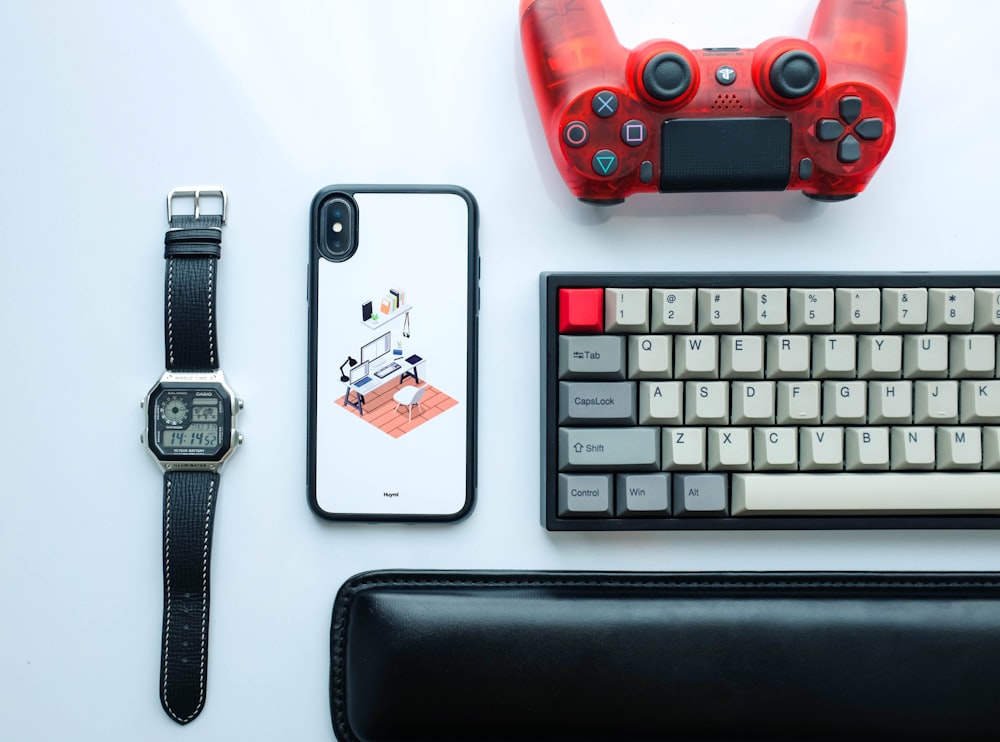 white and black iPhone X case beside silver-colored digital watch