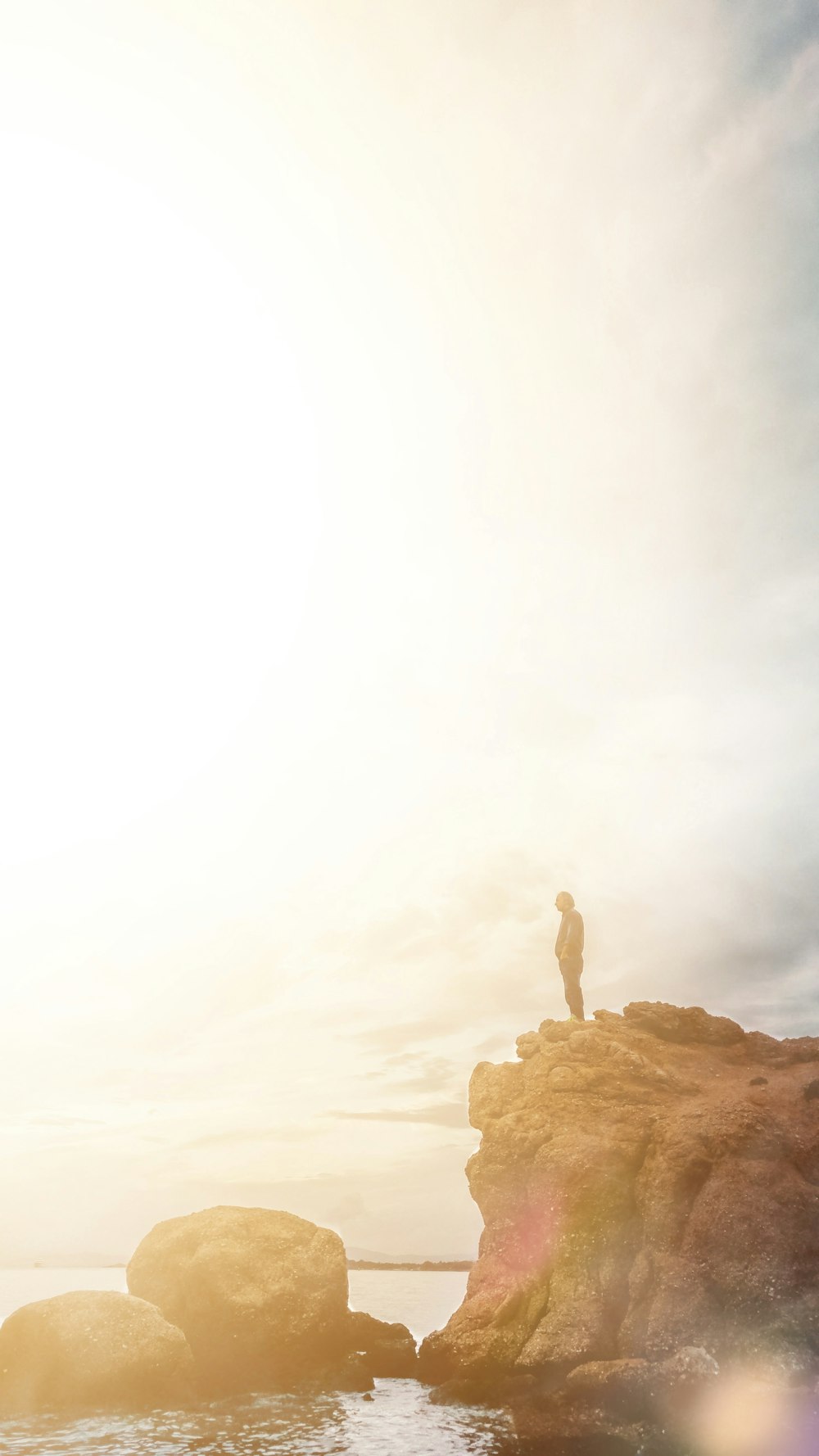 person standing on rock near ocean