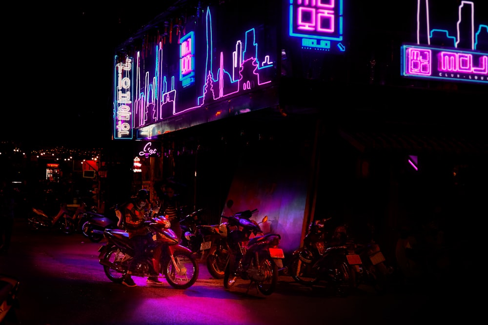motorcycles park under blue and pink LED signage
