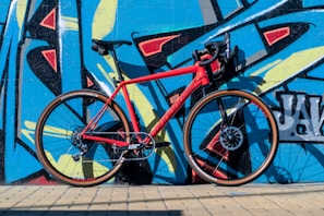 A sleek urban bike parked against a colorful graffiti wall on a sunny day
