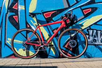 A sleek urban bike parked against a colorful graffiti wall on a sunny day