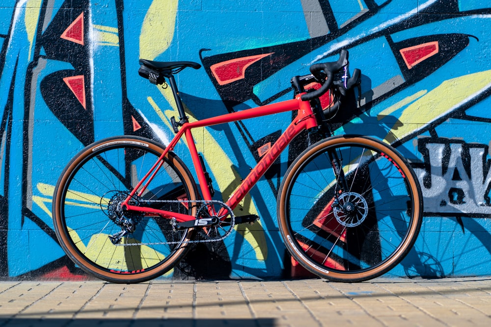 Bicicleta de carretera roja y negra estacionada junto a la pared azul