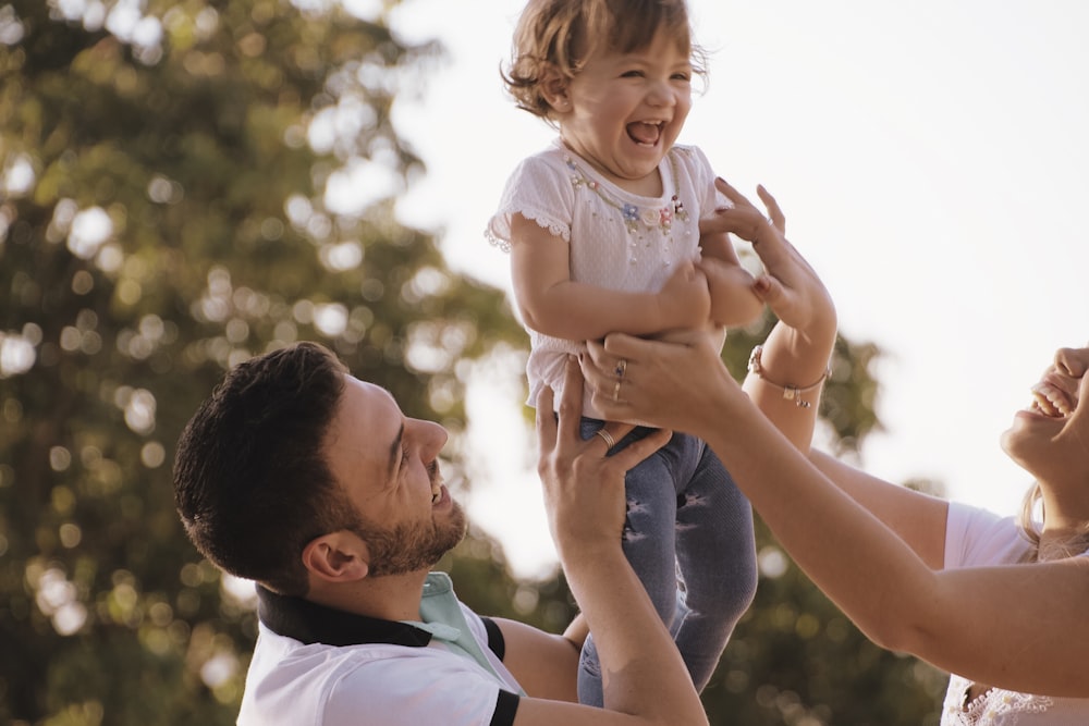 man and woman lifting girl