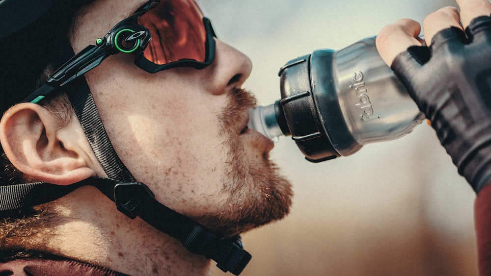 Un hombre con casco y gafas bebiendo de una botella de agua