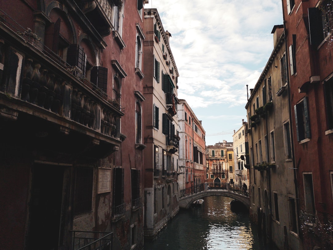 white bridge above canal in between buildings at daytime