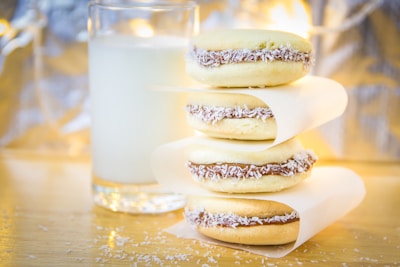 Freshly baked alfajores dusted with powdered sugar on a rustic wooden table.