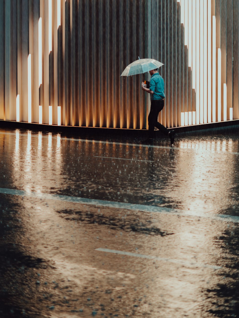 Mann mit Regenschirm, während er neben der Straße geht