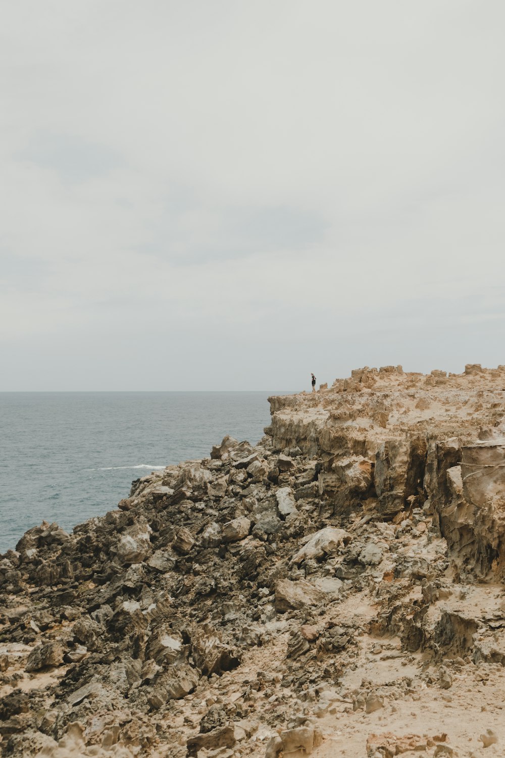 man standing on rock formation near body of water