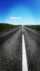 Finished smooth asphalt road stretching into the horizon under a blue sky.