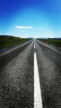 Finished smooth asphalt road stretching into the horizon under a blue sky.
