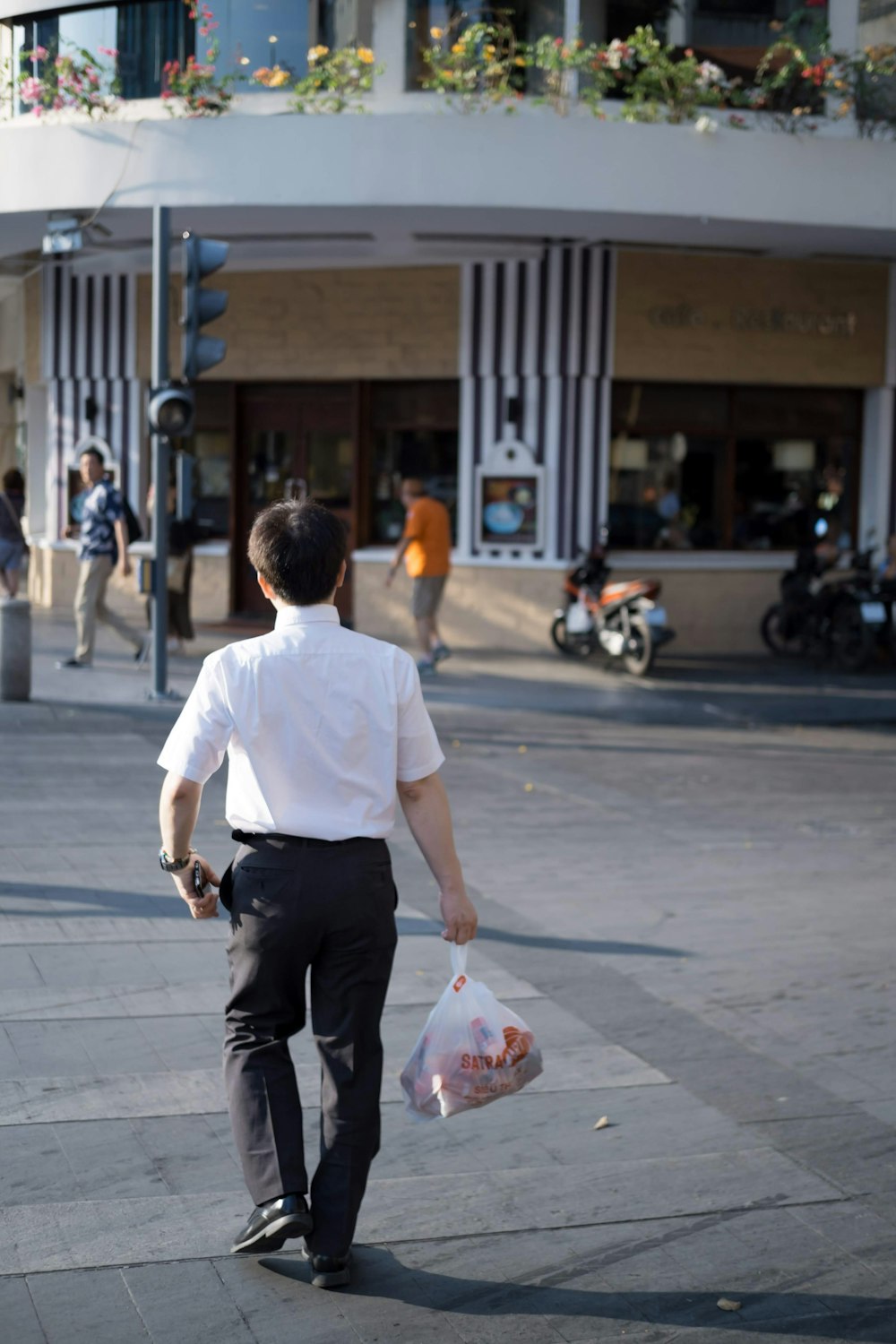 homem segurando saco plástico enquanto caminha no meio da rua