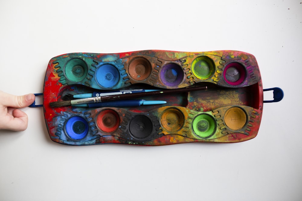 pessoa segurando paleta de tinta multicolorida retangular