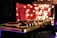 A DJ controller is prominently displayed with illuminated turntables and control knobs, set against a backdrop of vibrant bokeh lights, creating a festive and dynamic atmosphere.