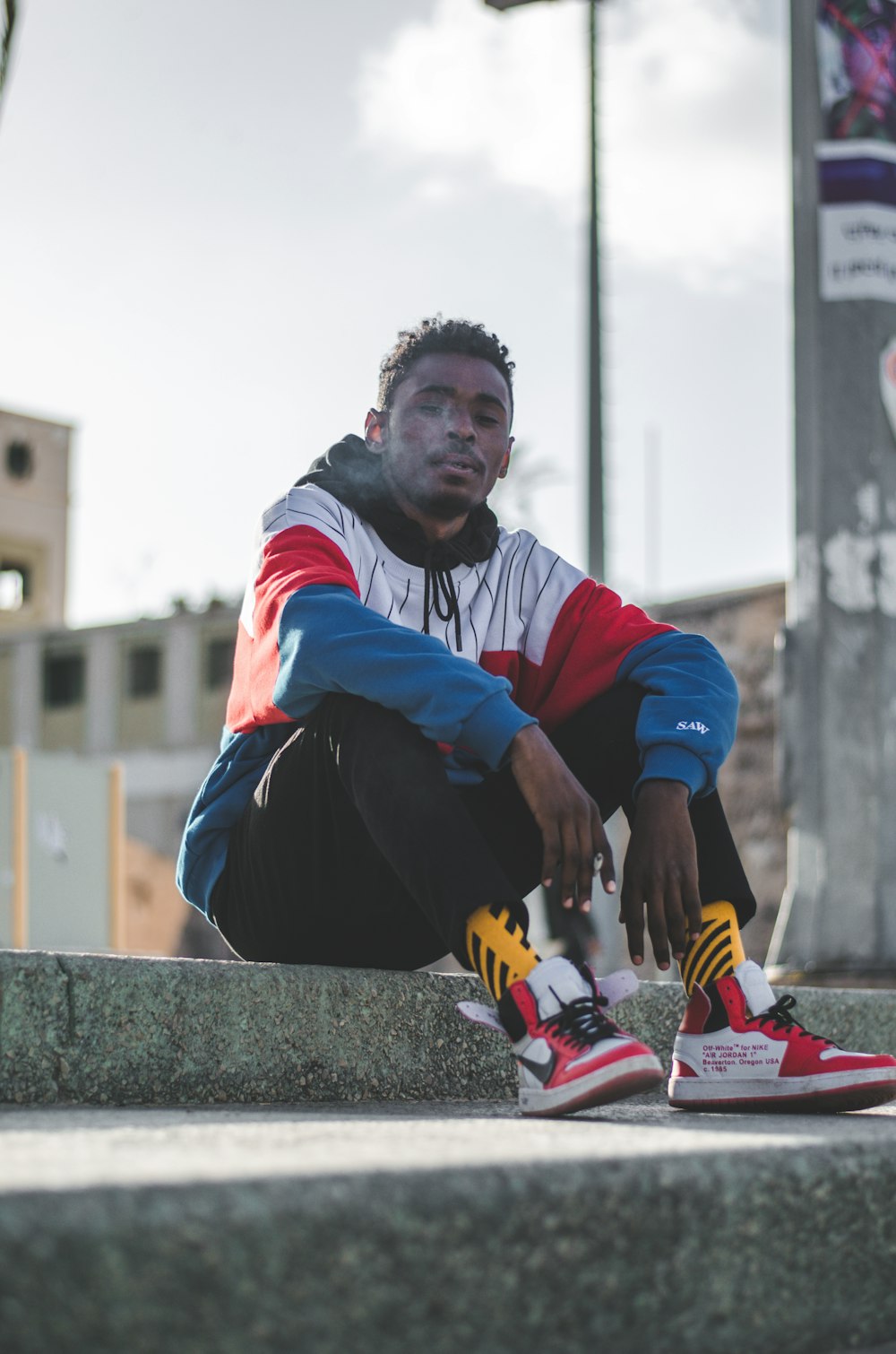 Hombre con sudadera con capucha roja, blanca y azul y zapatillas de baloncesto rojas y blancas