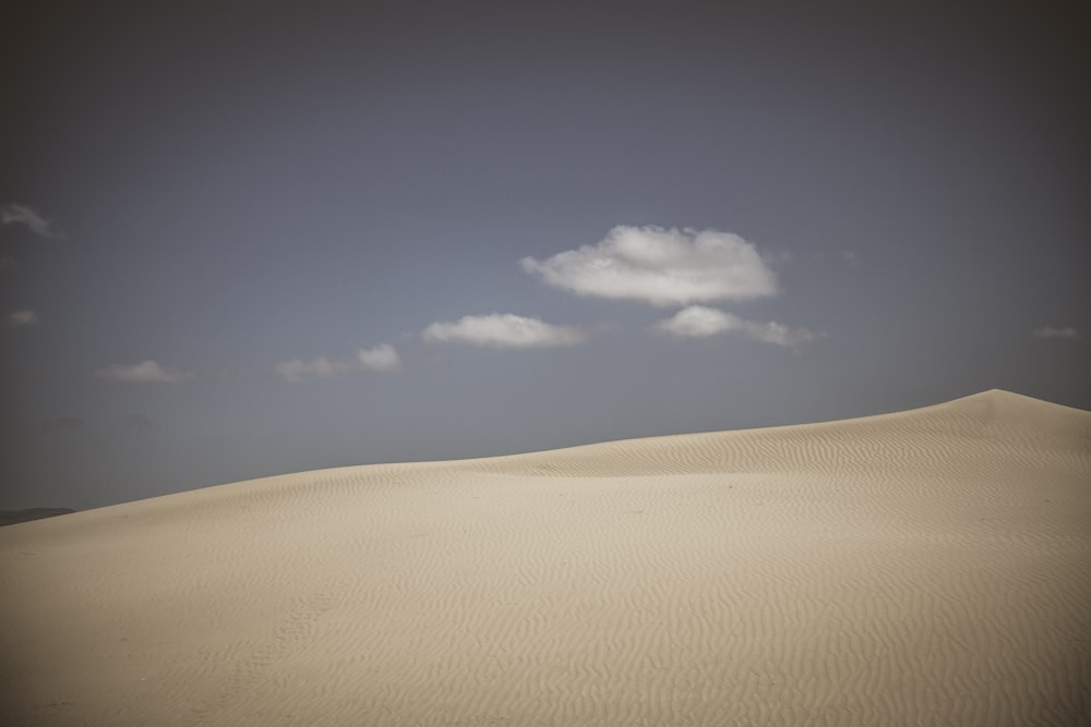 desert under white clouds and blue sky during daytime