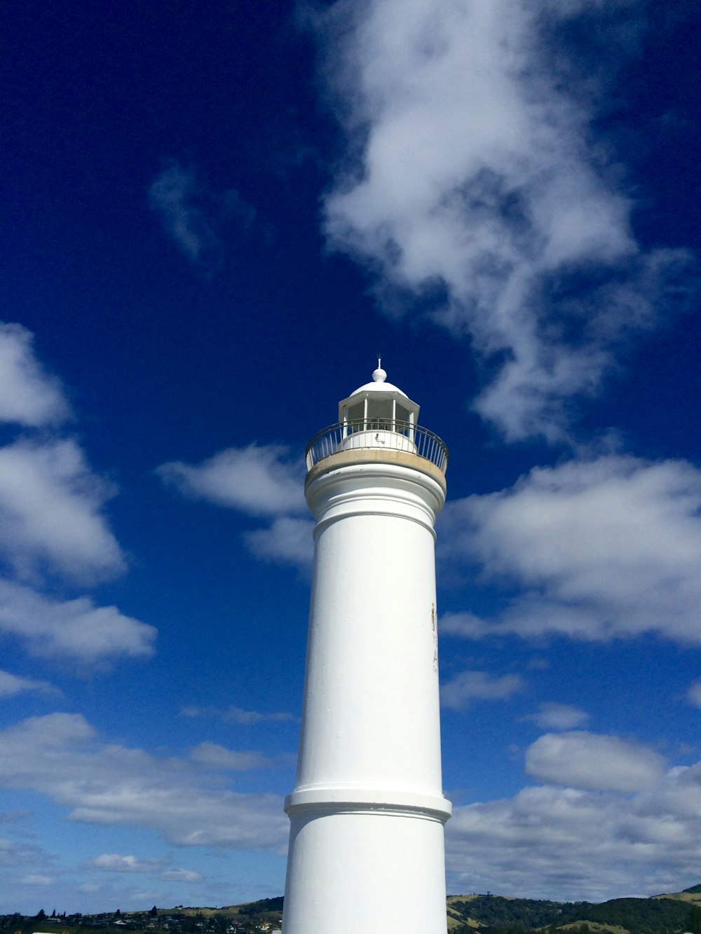 selective focus photography of white lighthouse under blue sky