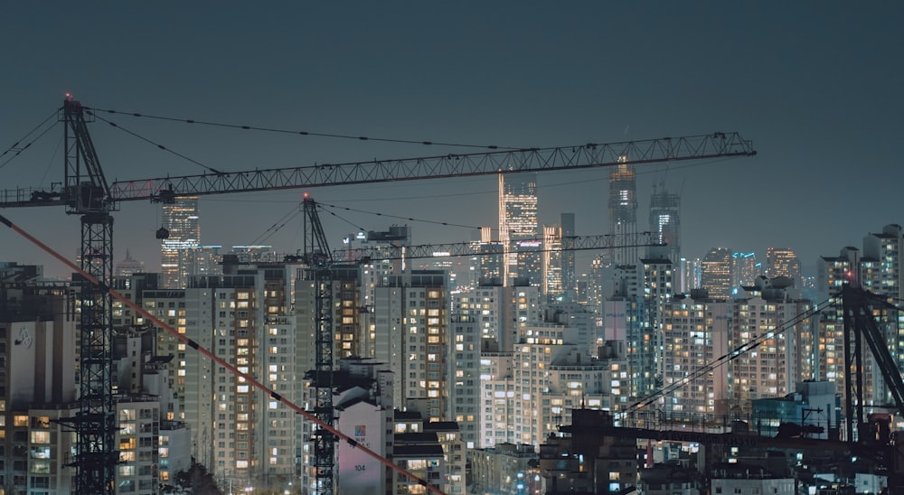 aerial photography of crane overlooking city buildings at night time