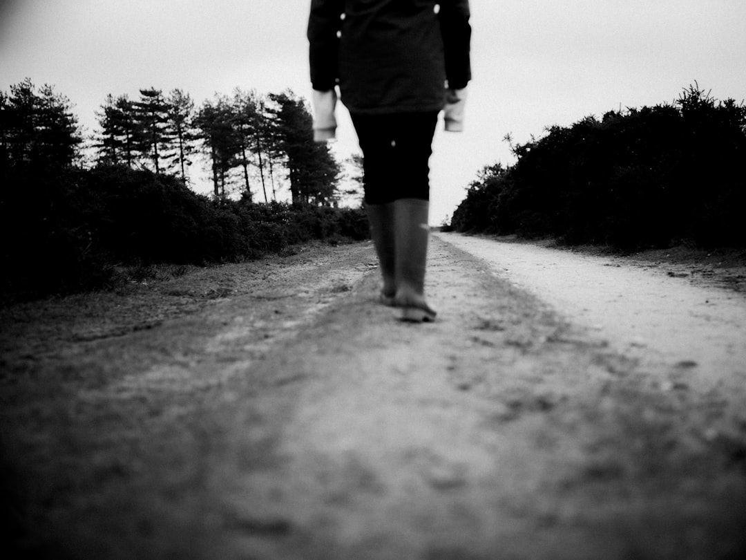 grayscale photo of person walking on road