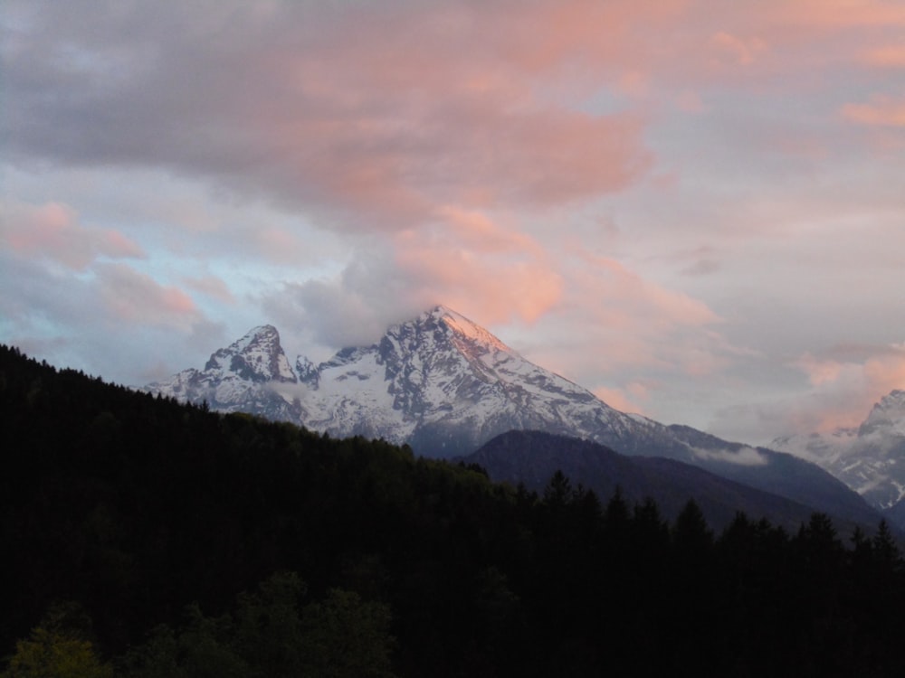 a mountain covered in snow under a cloudy sky