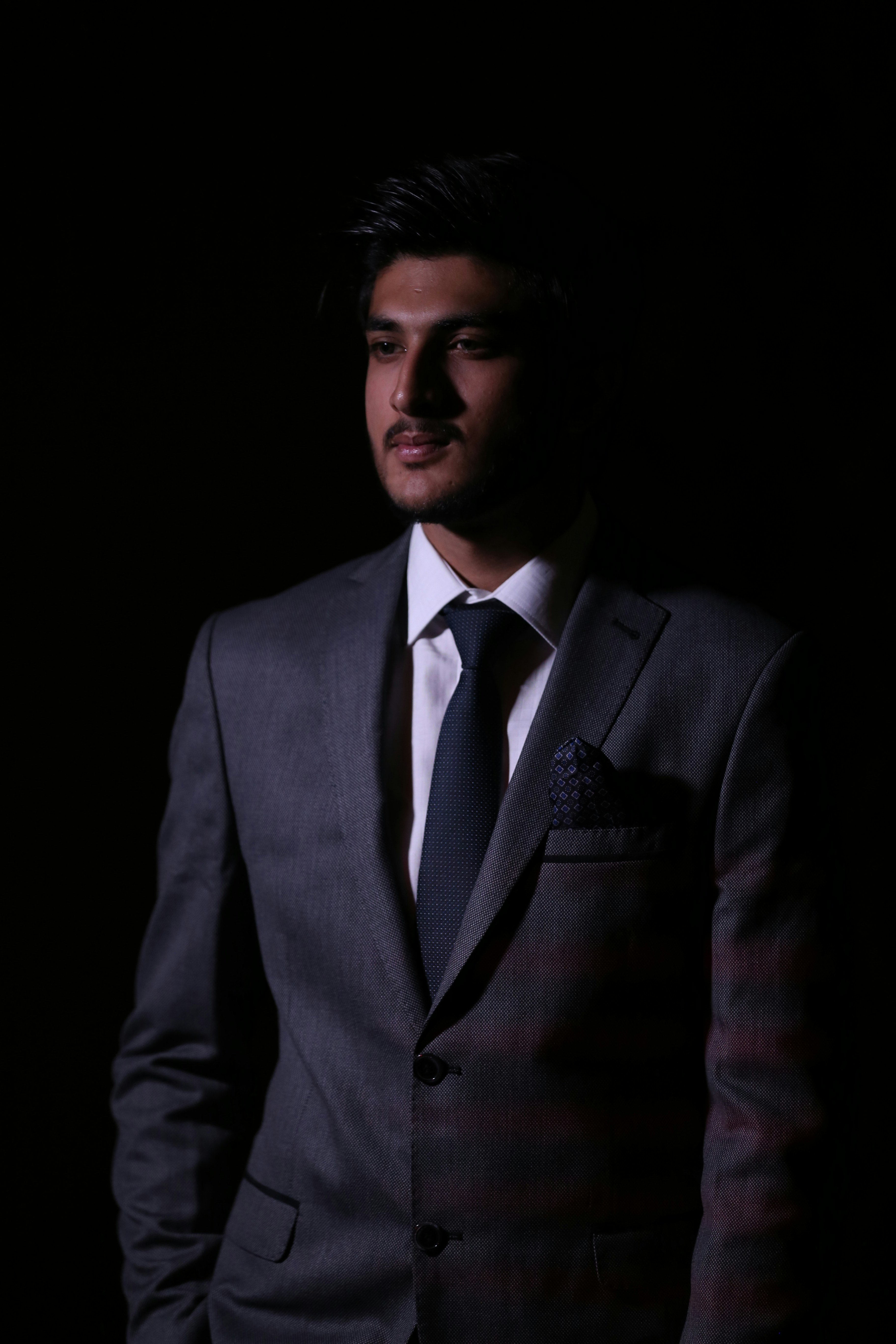 man wearing black suit standing inside dim lighted room