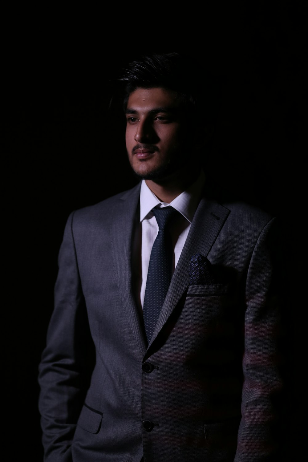 man wearing black suit standing inside dim lighted room