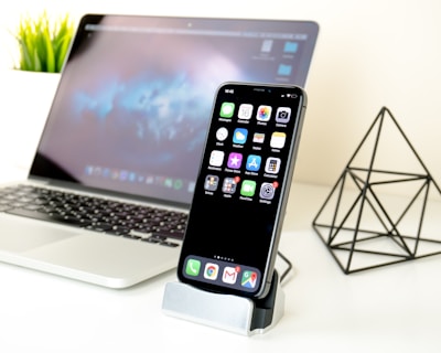 MacBook Pro near smartphone and black pyramid toy