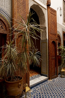 A warm Moroccan doorway framed by vibrant tiles and lush greenery, inviting visitors inside.