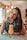 smiling woman sitting near table holding straw