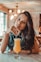 smiling woman sitting near table holding straw