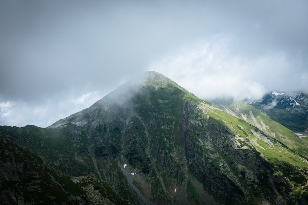 昼間の白い雲の下の緑と灰色の山