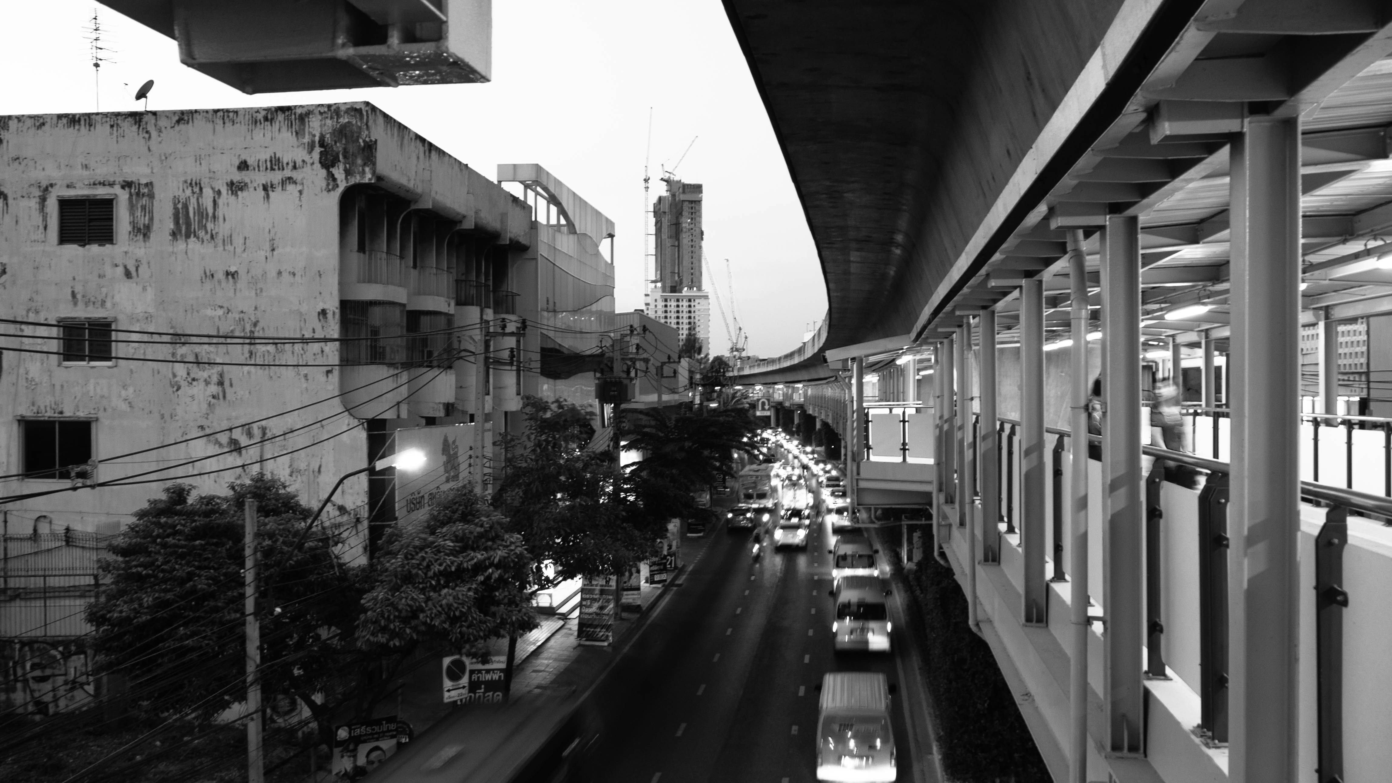 grayscale photo of vehicles traveling near buildings